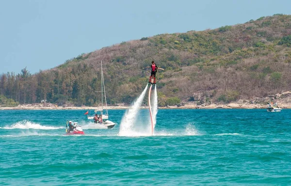 Hainan, Sanya, China - 14 de maio de 2019: Flyboarding. Voando sobre a água no tabuleiro com um poderoso jato de água. Atracção na praia. Desporto extremo e recreação . — Fotografia de Stock