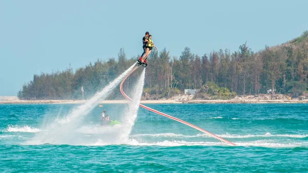 Hainan, Sanya, China - 14 de maio de 2019: Flyboarding. Voando sobre a água no tabuleiro com um poderoso jato de água. Atracção na praia. Desporto extremo e recreação . — Fotografia de Stock