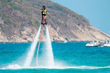 Hainan, Sanya, Çin - 14 Mayıs 2019: Flyboarding. Güçlü bir su jetiyle tahtanın üzerinde suyun üzerinde uçuyor. Sahilde cazibe. Ekstrem spor ve rekreasyon.