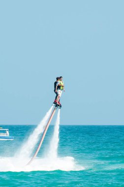 Hainan, Sanya, Çin - 14 Mayıs 2019: Flyboarding. Güçlü bir su jetiyle tahtanın üzerinde suyun üzerinde uçuyor. Sahilde cazibe. Ekstrem spor ve rekreasyon.