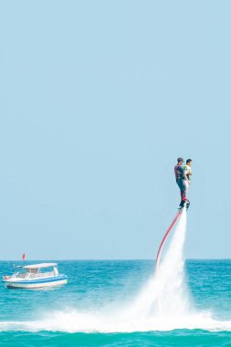 Hainan, Sanya, Çin - 14 Mayıs 2019: Flyboarding. Güçlü bir su jetiyle tahtanın üzerinde suyun üzerinde uçuyor. Sahilde cazibe. Ekstrem spor ve rekreasyon.