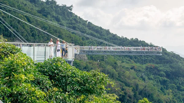 Hainan, China - 17 de mayo de 2019: Cubierta de observación en forma de puente de cristal. Parque Forestal Yanoda - las montañas están cubiertas de selvas tropicales . —  Fotos de Stock
