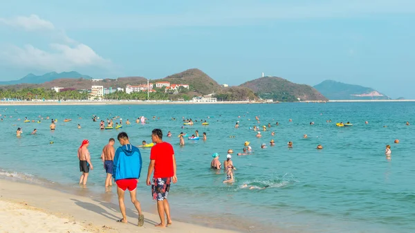 Hainan, Chiny-14 maja 2019: w jasny słoneczny dzień na tropikalnej plaży, ludzie pływają w morzu, zrelaksować się na piasku. — Zdjęcie stockowe