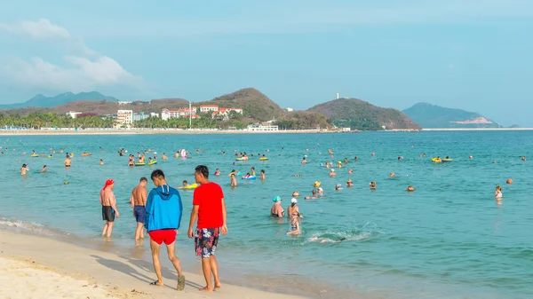Hainan, Çin-14 Mayıs 2019: tropikal bir plajda parlak güneşli bir gün, insanlar Denizde yüzerek, kum üzerinde dinlenmek.