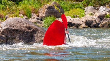 Oyun teknesi. Elinde küreklerle kayıkta oturan bir adam su üzerinde egzersiz yapar. Whitewater üzerinde serbest kayak. Eskimo rulo.