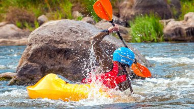 Oyun teknesi. Elinde küreklerle kayıkta oturan bir adam su üzerinde egzersiz yapar. Whitewater üzerinde serbest kayak. Eskimo rulo.