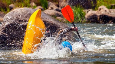Oyun teknesi. Elinde küreklerle kayıkta oturan bir adam su üzerinde egzersiz yapar. Whitewater üzerinde serbest kayak. Eskimo rulo.
