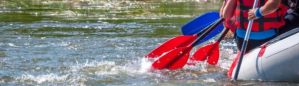 Rafting trip. Close up view of oars with splashes of water. Rowers make an effort to overcome the turbulent river. The concept of teamwork, healthy lifestyle.