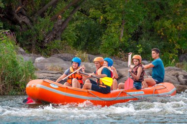 Myhia, Ukrayna - 17 Ağustos 2019: Rafting. Erkek ve kadın neşeli bir grup nehir üzerinde büyük bir şişme tekne üzerinde iner. Mutlu insanların samimi duyguları.