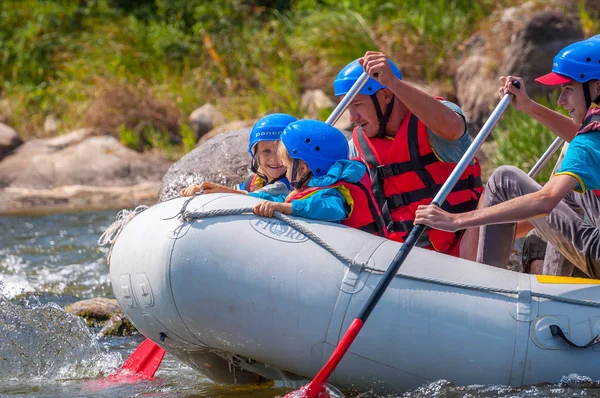 Myhia, Ukrayna - 17 Ağustos 2019: Rafting. Erkek ve kadın neşeli bir grup nehir üzerinde büyük bir şişme tekne üzerinde iner. Teknede bir çocuk var. Mutlu insanların samimi duyguları.