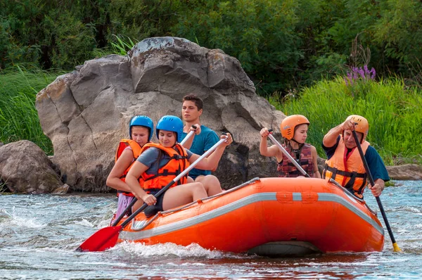 Myhia, Ukrayna - 17 Ağustos 2019: Rafting. Erkek ve kadın neşeli bir grup nehir üzerinde büyük bir şişme tekne üzerinde iner. Mutlu insanların samimi duyguları.