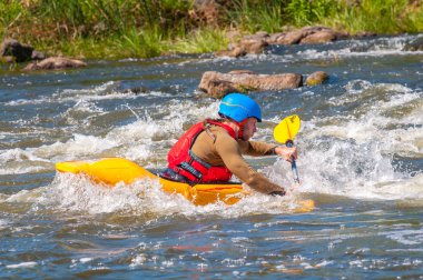 Myhiya, Ukrayna - 17 Ağustos 2019: Playboating. Elinde küreklerle kayıkta oturan bir adam su üzerinde egzersiz yapar. Whitewater üzerinde kayak serbest stil.