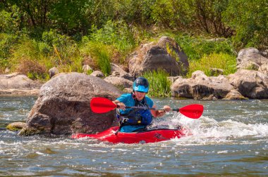 Myhiya, Ukrayna - 17 Ağustos 2019: Playboating. Elinde küreklerle kayıkta oturan bir adam su üzerinde egzersiz yapar. Whitewater üzerinde kayak serbest stil.