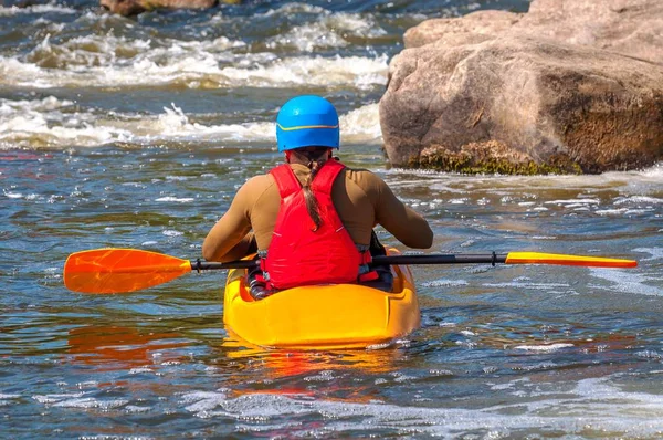 Un kayak con remos en marcha completa está sentado en un kayak sobre agua blanca. Vista trasera —  Fotos de Stock