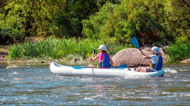 Rafting. İki kız nehirüzerinde büyük bir şişme kayık üzerine inerler. Bir kürek ile satır, ve diğer satır değil ve bir akıllı telefon kullanarak bir rapor yapar.