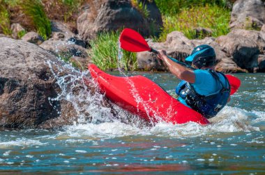 Oyun teknesi. Elinde küreklerle kayıkta oturan bir adam su üzerinde egzersiz yapar. Whitewater üzerinde serbest kayak. Eskimo rulo.