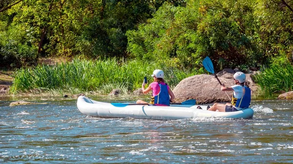 Rafting. Dos chicas descienden en un gran kayak inflable en el río. Uno remaba con remos, y el otro no remaba y hacía un informe usando un smartphone . —  Fotos de Stock