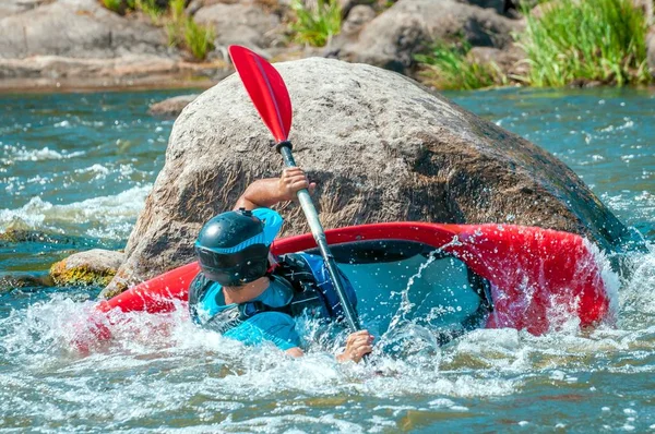 Giocando in barca. Un uomo seduto in kayak con i remi in mano fa esercizi sull'acqua. Kayak freestyle su whitewater. Rotolo eschimese . — Foto Stock