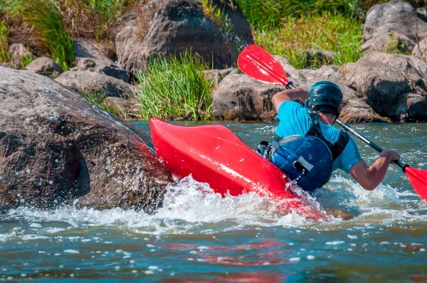 Playboating. A man sitting in a kayak with oars in his hands performs exercises on the water. Kayaking freestyle on whitewater. Eskimo roll.