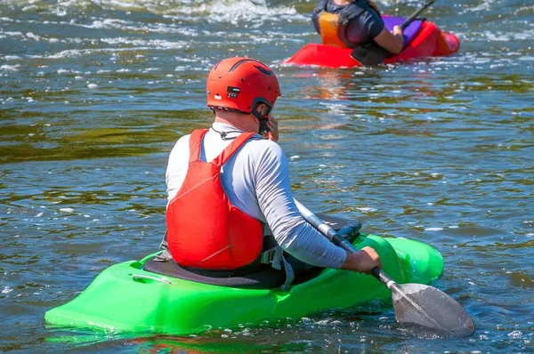 Spielbootfahren. Ein Mann, der in einem Kajak sitzt und Ruder in den Händen hält, macht Übungen auf dem Wasser. Kajak-Freestyle auf Wildwasser. — Stockfoto
