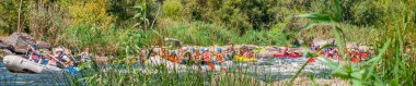 Myhiya, Ukraine - August 17, 2019: Rafting trip. A flotilla of several large inflatable boats descends along a fast, stony river. clipart