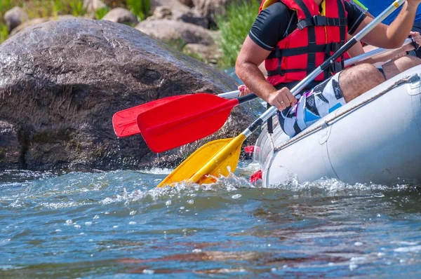 Rafting trip. Close up view of oars with splashes of water. Rowers make an effort to overcome the turbulent river. The concept of teamwork, healthy lifestyle.