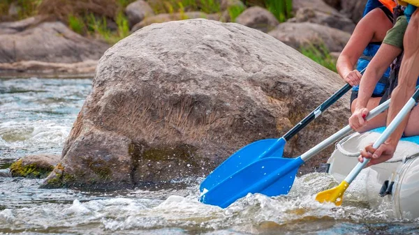 Rafting trip. Close up view of oars with splashes of water. Rowers make an effort to overcome the turbulent river. The concept of teamwork, healthy lifestyle.