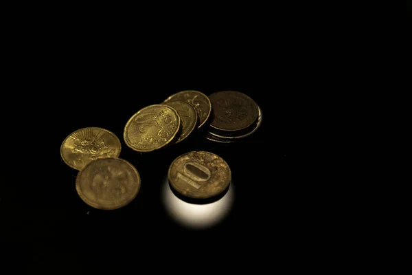 there are some coins on the black surface. coins are on the light