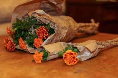 Ambalaj kağıdındaki karanfiller masanın üstünde.