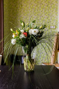 Masadaki vazoda bir buket çiçek.