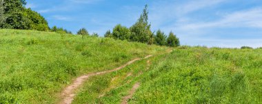 Panoramik pastoral manzara-bir yaz gününde tepelerde bir çayır yoluyla yol