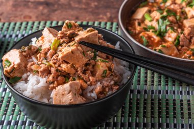 Popüler bir Çin Sichuan çanak baharatlı Mapo tofu ile pirinç bir kase ve bir bambu peçete Mapo soya peyniri bir plaka