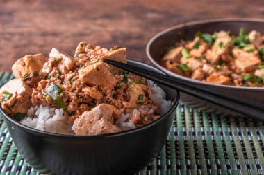Popüler bir Çin Sichuan çanak baharatlı Mapo tofu ile pirinç bir kase ve bir bambu peçete Mapo soya peyniri bir plaka