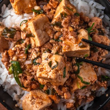 Popüler Çin Sichuan çanak-rustik ahşap masa üzerinde Mapo soya peyniri ile pirinç bir kase, üst görünüm, yakın çekim