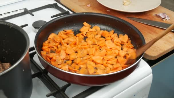 ニンジンはソース クローズアップ 木製のスプーンを作るために自宅で鍋に揚げられています 健康的な食事食品 — ストック動画
