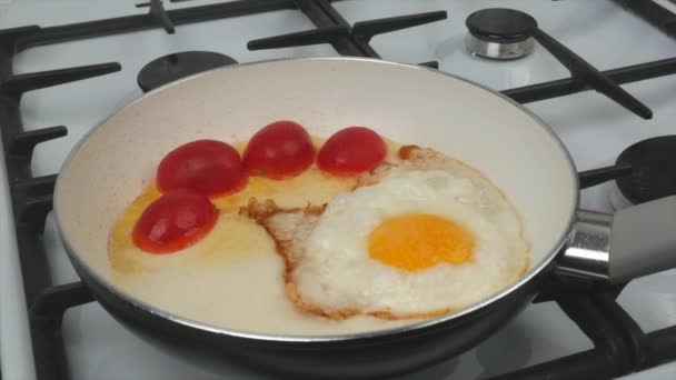 Petit déjeuner rapide - œufs, tomates et saucisses sont frits dans une poêle avec un revêtement antiadhésif blanc