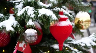 Üzerinde kar olan ladin dalları ve ön planda Noel oyuncakları ve arka planda kış sokağı.