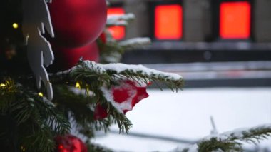 Üzerinde kar olan ladin dalları ve ön planda Noel oyuncakları ve arka planda kış sokağı.