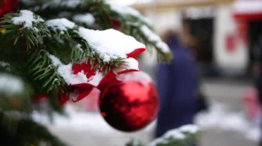 Üzerinde kar ve Noel oyuncakları olan ladin dalları - ön planda kırmızı toplar ve arka planda kış sokağı