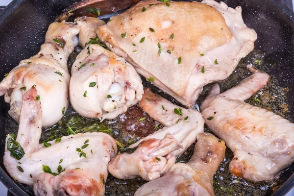 Kızartma tavasında kekik ve biberiyeli tavuk pişirmek. Yakın çekim, üst manzara.