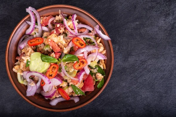 İtalyan tuscan vejetaryen panzanella salatası, ekmeklerden, domateslerden ve sebzelerden oluşan karışık salata siyah bir taş yüzeyde, üst manzara, kopyalama alanı.