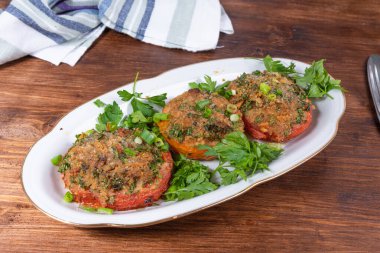 Provenkal domatesler, oval bir çanakta ekmek kırıntıları ve otlarla pişirilmiş domates parçaları, kırsal bir arka plan.