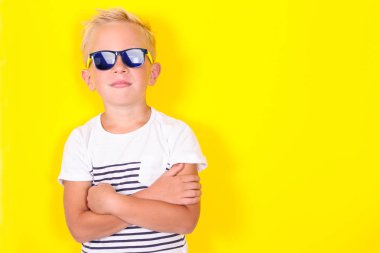 Hoş serin sarışın çocuk güneş gözlüğü takıyor sarı arka plan üzerinde parlak portpait