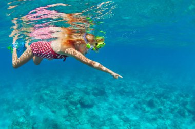 Su altı dünyasını keşfetmek için mercan resiflerinde dalış yapan maske takan çocuklu genç bir anne. Yaz macera kampında aile seyahati yaşam tarzı. Çocuklarla plaj tatilinde yüzme aktiviteleri.