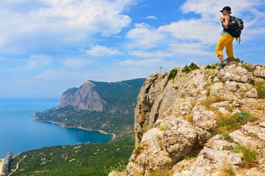 Genç aktif kadın dağın tepesinde duruyor. İnanılmaz deniz manzarasına bak. Aile seyahati macerası, yürüyüş aktivitesi, sağlıklı yaşam tarzı, yaz tatilinde doğayı keşfetmek. Hafta sonu yürüyüş turu.