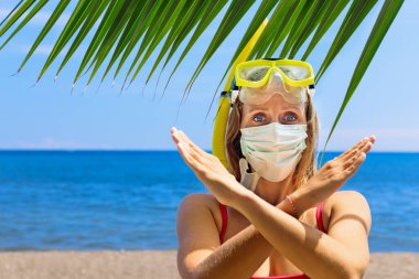 Şnorkel maskeli kız deniz sahilinde cerrahi maske takıyor. Geziler iptal edildi, Coronavirus COVID 19 dünya salgını nedeniyle turlar iptal edildi. Aile tatili için seyahat yasağı, 2020 yazında turizm sektörü krizi