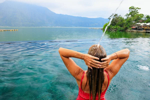 年轻女子在无限大的游泳池里 在流动的水底悠闲 湖景秀丽 巴图尔火山旁边的天然温泉温泉 在巴厘岛Kintamani的旅游 家庭暑假旅游生活方式 — 图库照片