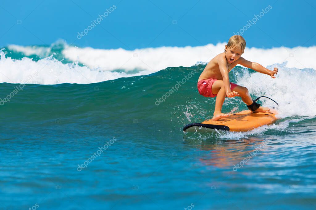 Happy baby boy - young surfer learn to ride on surfboard with fun on sea waves. Active family lifestyle, kids outdoor water sport lessons, swimming activity in surf camp. Summer vacation with child.