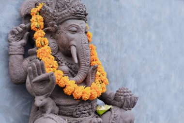 Ganesha, yoga yaparken Hindu tapınağının önünde poz veriyor. Dini festival için portakal çiçekleriyle süslenmiş çelenkler, törensel hediyeler. Bali seyahat geçmişi. Bali adası sanatı, kültür.