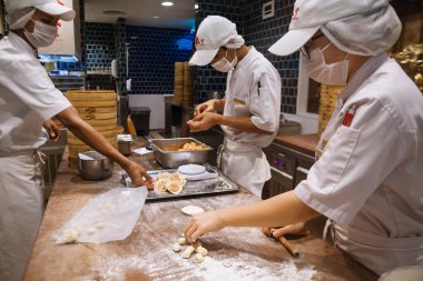 Johor, Malezya - 22 Mart 2018: Asyalı aşçılar Tayvan hamur köftesi restoranında geleneksel Çin yemekleri pişiriyorlar. Erkekler Xiao long bao, mantou, dim sum olarak bilinen taze çöreklerden pişirir ve hamur yaparlar..